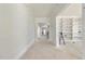Spacious hallway with white walls and light hardwood floors leading to a built-in bookcase room and staircase at 1221 Dixie Trl, Raleigh, NC 27607