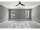 Bedroom with gray walls, a dark ceiling fan, white trim, and two windows that brighten the space at 1229 Dixie Trl, Raleigh, NC 27607