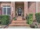 Inviting front porch with brick steps, black railings and planters overflowing with colorful flowers at 12412 Mayhurst Pl, Raleigh, NC 27614