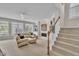 Spacious living room with fireplace, built-ins, large windows, and staircase to the upper level at 12412 Mayhurst Pl, Raleigh, NC 27614