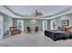 Spacious main bedroom featuring a tray ceiling, ceiling fan, and ample natural light from multiple windows at 12412 Mayhurst Pl, Raleigh, NC 27614