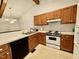Efficient kitchen with wood cabinets, white appliances, and a practical layout adjacent to a dining area at 1306 Oakridge Ave, Henderson, NC 27536