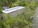 Aerial view of a brick building with a white roof nestled amongst green trees and beside a flowing river at 1500 River Mill Dr # 310, Wake Forest, NC 27587