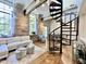 Inviting living room with a spiral staircase, stone walls, hardwood floors, and lots of natural light from large windows at 1500 River Mill Dr # 310, Wake Forest, NC 27587