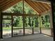 Spacious screened porch with wood flooring and exposed beams, overlooking a lush, wooded backyard at 152 Big Bradley Dr, Wendell, NC 27591