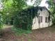 Back of the house partially covered in climbing vines, showing brick shutters and surrounded by mature landscaping at 1806 Rendall St, Burlington, NC 27215
