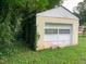 A backyard garage door is seen with a window and vines on the building at 1806 Rendall St, Burlington, NC 27215