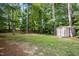 Backyard with storage shed surrounded by mature trees and lush greenery at 210 Water Oak Way, Louisburg, NC 27549
