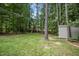 Spacious backyard featuring a large grassy area, mature trees, and a convenient storage shed at 210 Water Oak Way, Louisburg, NC 27549