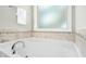 Soaking tub with tile backsplash and a chrome faucet under a frosted window at 210 Water Oak Way, Louisburg, NC 27549