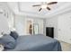 Spacious bedroom with ensuite bathroom features a tray ceiling, ceiling fan, and is brightly lit by bedside lamps at 210 Water Oak Way, Louisburg, NC 27549