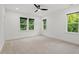 Bright bedroom with neutral carpet, white walls, and three large windows offering a leafy view at 2124 Country Air Ln, Hillsborough, NC 27278