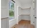 Bright walk-in closet with custom shelves, wooden trim and floors, and a window overlooking a wooded area at 2124 Country Air Ln, Hillsborough, NC 27278