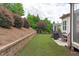 Spacious backyard with green grass, retaining wall, and lush landscaping is great for outdoor activities at 236 Lucky Ribbon Ln, Holly Springs, NC 27540
