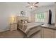 Well-lit bedroom featuring a large bed with decorative pillows, neutral color scheme, ceiling fan, and a dresser with TV at 2730 Spring Valley Dr, Creedmoor, NC 27522