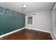 Stylish bedroom with hardwood flooring, a green accent wall, and patterned wallpaper above paneling at 2801 E Shoreham St, Durham, NC 27707