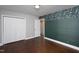 Bedroom with wood flooring, green accent wall, and lots of closet space at 2801 E Shoreham St, Durham, NC 27707