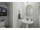 Small powder room with a white pedestal sink, a round mirror, and neutral wall color at 2925 Dargan Hills Dr, Wake Forest, NC 27587
