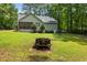 Backyard view featuring a fire pit, green lawn, and wooded surroundings at 296 Gordon Farm Dr, Benson, NC 27504