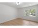 Bright, minimalist bedroom features hardwood floors, neutral walls, and a window showcasing lush greenery at 3032 Dixon Rd, Durham, NC 27707
