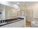 Elegant bathroom with double sinks, granite countertops, a large mirror, glass shower, and soaking tub at 315 Allister Dr, Raleigh, NC 27609
