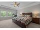 Spacious main bedroom featuring a tray ceiling, ceiling fan, and plentiful natural light at 317 Striped Maple Ct, Apex, NC 27539