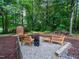 Cozy backyard fire pit area with gravel base, mulched landscape, and wooded views at 3400 Appling Way, Durham, NC 27703