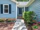 Close-up of the home's front door, featuring a blue door with a small window and brick foundation at 3400 Appling Way, Durham, NC 27703