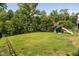 Spacious backyard featuring a lush lawn, mature trees, and a playset for outdoor fun at 5028 Blue Jack Oak Dr, Cary, NC 27519