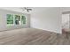 Spacious living room with a ceiling fan, wood-look flooring, and three large bright windows overlooking the backyard at 5028 Blue Jack Oak Dr, Cary, NC 27519