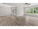 Bright living room with wood-look flooring, a ceiling fan, and multiple windows and a door for backyard access at 5028 Blue Jack Oak Dr, Cary, NC 27519