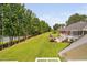 Expansive backyard view featuring lush lawn, mature trees, outdoor patio, and lake at 6708 Wavcott Dr, Fuquay Varina, NC 27526