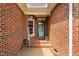 Inviting brick-covered front porch with a welcoming welcome sign, beautiful flower arrangement, and a stylish blue front door at 6708 Wavcott Dr, Fuquay Varina, NC 27526