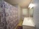 Cozy bathroom featuring a shower with curtain, sink, mirror, and patterned wallpaper at 6717 Valley Dr, Raleigh, NC 27612