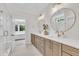 Bright bathroom featuring dual sinks, quartz countertop, walk-in shower, and linen cabinetry at 800 Wilcox St, Raleigh, NC 27607