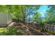 View of backyard with a wooden fence, grassy lawn, and mature trees and landscaping at 916 Woodside Park Ln, Durham, NC 27704