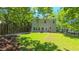 Expansive backyard with lush lawn, patio seating, mature trees, and wooden fence around perimeter at 916 Woodside Park Ln, Durham, NC 27704