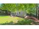 Backyard featuring patio seating, grassy lawn, mulched areas, and mature trees for privacy at 916 Woodside Park Ln, Durham, NC 27704
