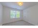 Carpeted bedroom features a large window, double closet, and neutral paint at 916 Woodside Park Ln, Durham, NC 27704