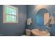 Stylish half bathroom features a modern sink, round mirror, and well-placed window for natural light at 916 Woodside Park Ln, Durham, NC 27704