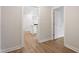 Hallway with hardwood floors leading to the bright kitchen with white cabinetry and modern appliances at 94 Black Walnut Dr # 201, Garner, NC 27529