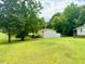 View of the detached garage near the home surrounded by a grassy lot with mature trees at 94 S Waters Edge Ln, Henderson, NC 27537