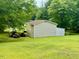 View of the side and rear of the detached garage outbuilding surrounded by a grassy lot at 94 S Waters Edge Ln, Henderson, NC 27537
