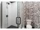 Sleek bathroom featuring a glass shower, white tile, black accents, and decorative wallpaper at 9940 Koupela Dr, Raleigh, NC 27614
