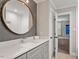 Bathroom with round mirror over grey vanity and white quartz countertop at 9940 Koupela Dr, Raleigh, NC 27614