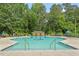 Community pool with multiple lounge chairs and mature trees in background at 9940 Koupela Dr, Raleigh, NC 27614