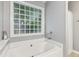 Close-up of the bathtub and unique glass block window in the bathroom at 10 Oxford Dr, Angier, NC 27501
