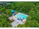 Aerial view of a community pool with many lounge chairs and sun umbrellas, surrounded by mature green trees at 100 Fountain Springs Rd, Holly Springs, NC 27540