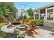Backyard retreat with a stone fire pit, Adirondack chairs, string lights, and lush landscaping at 100 Fountain Springs Rd, Holly Springs, NC 27540