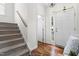 Bright foyer with staircase, hardwood floors, and an inviting entry door, showcasing modern design and natural light at 100 Fountain Springs Rd, Holly Springs, NC 27540